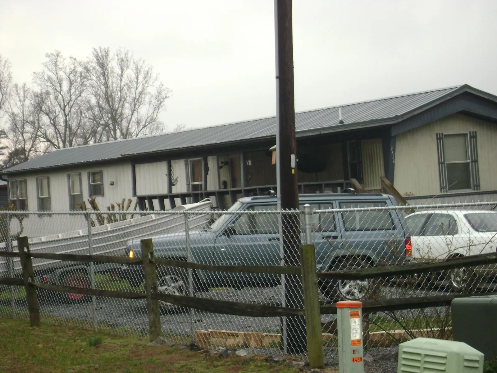 Dark metal roof on a long single story building behind a chain link fence in Lexington